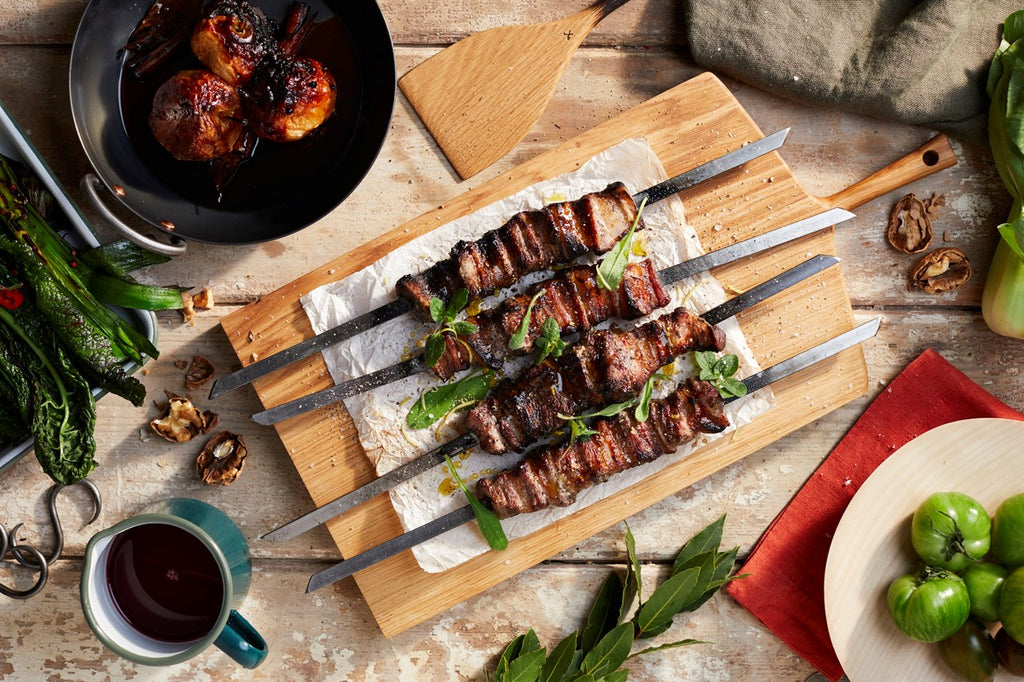 BBQ pork belly skewers, caramelised apples. Made using flat skewers, heavy based skillet, enamel gravy jug, hand carved wooden board with handle, shallow bowl carved by hand, Autumn BBQ recipe, Autumn barbecue ideas